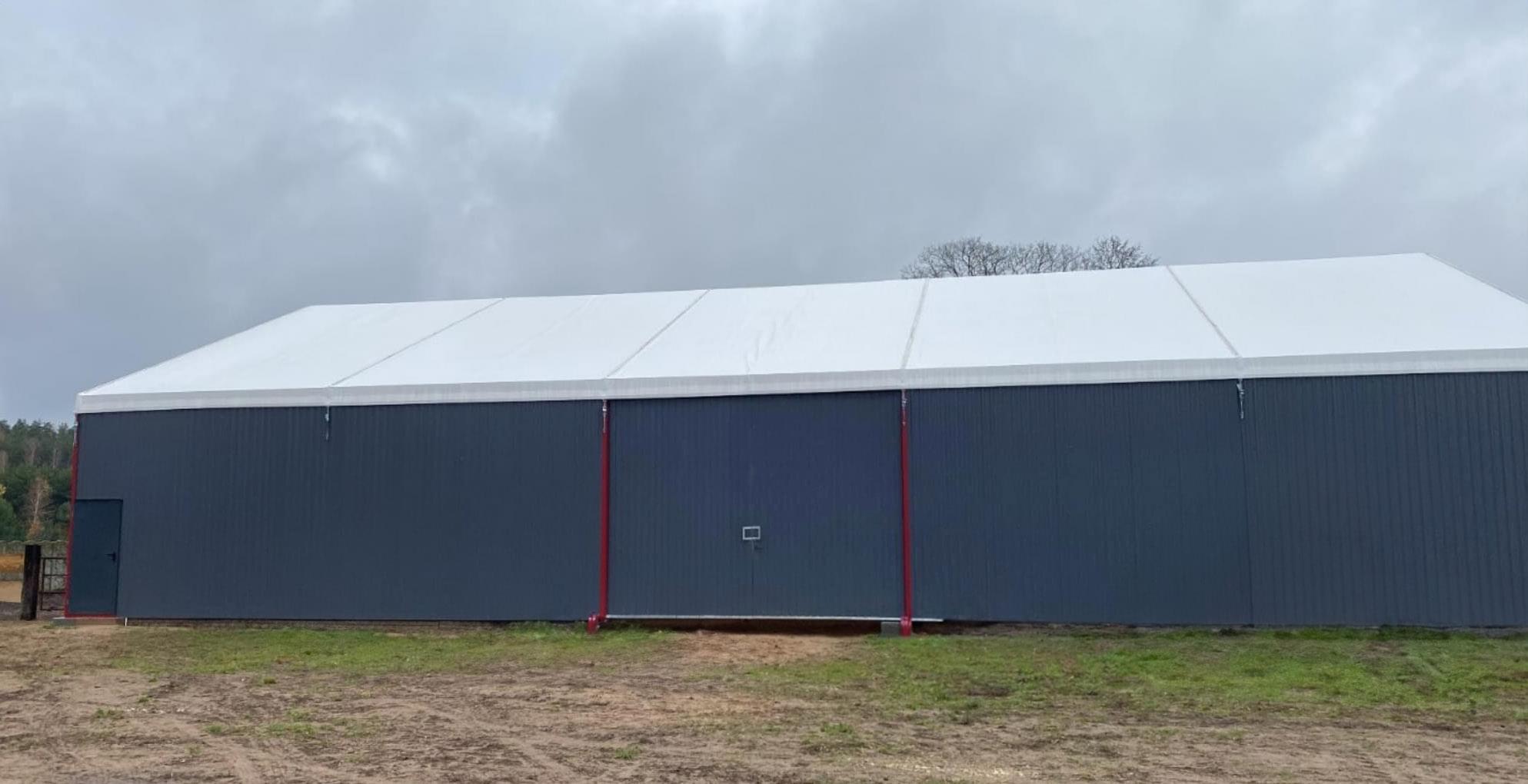 zdjęcie hali z białym dachem stojącej na trawie